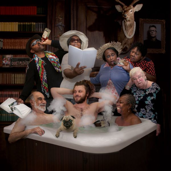 A group of eight people, three of them are in a hot tub, the other five stand behind the hot tub.