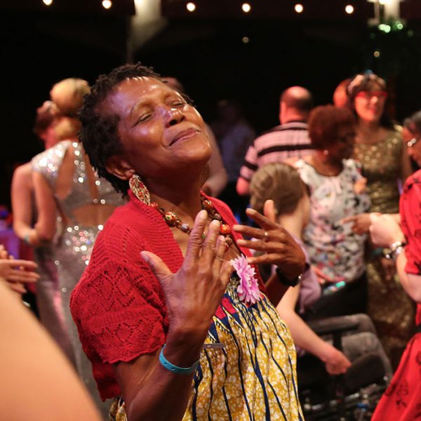 A woman with her head raised, eyes closed and hands to her chest.