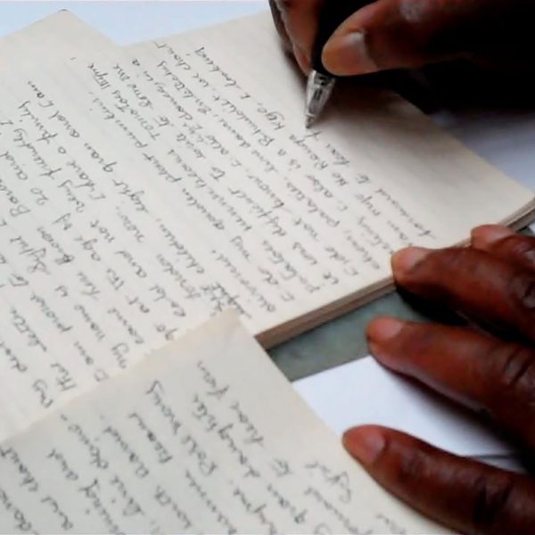 A close up of a hand writing in a notebook.