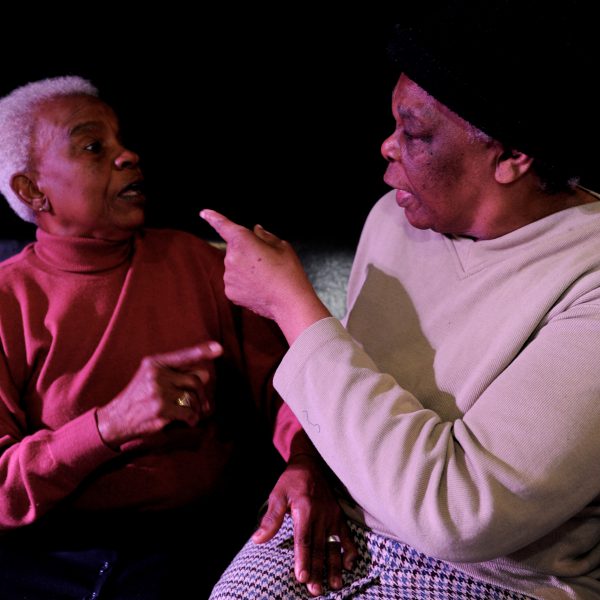 Two women pointing at each other.
