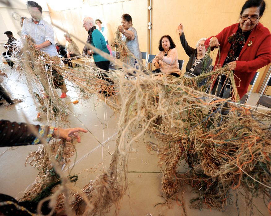 many people with a spiderweb of wool