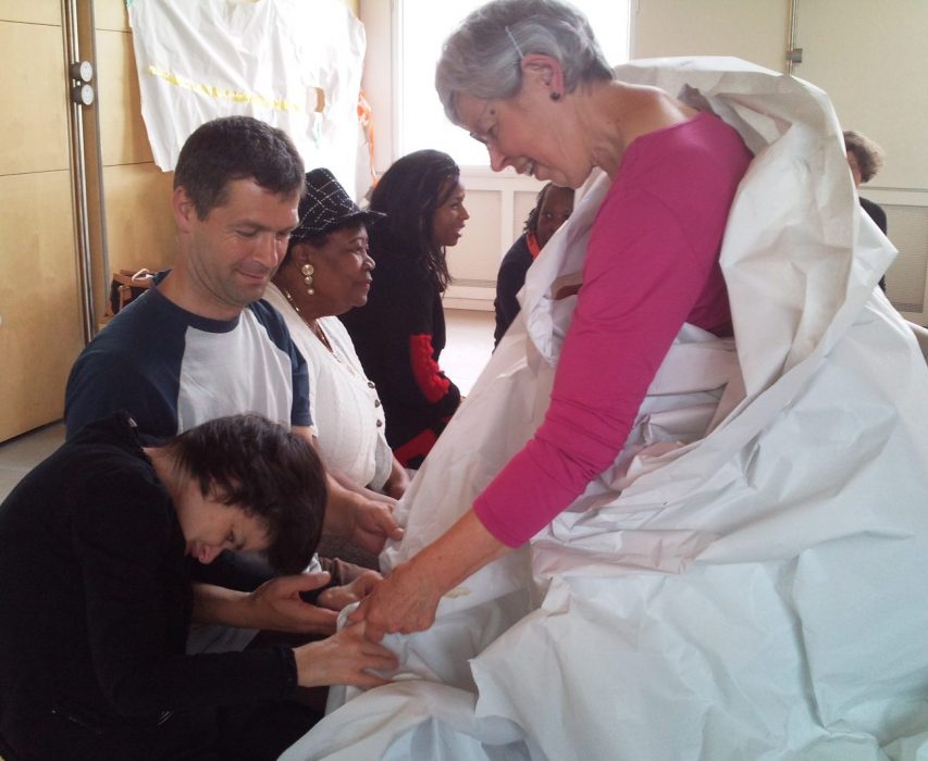 older person wrapped in sheet holding hands with participant