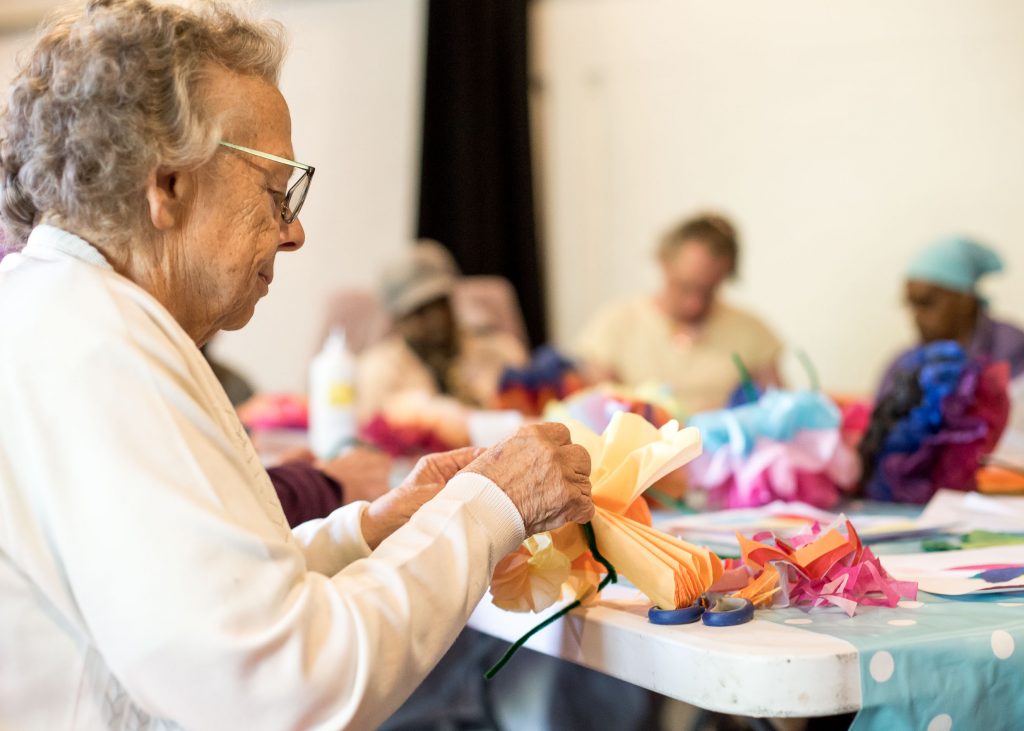 older person making paper flowers