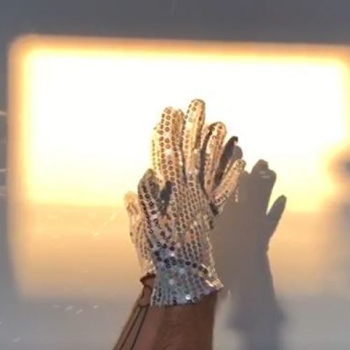 hands with glitter gloves in a square of light