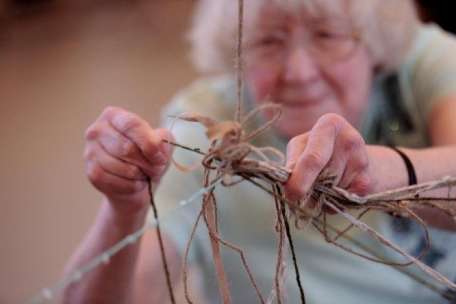 Older woman making a sculpture with string and sticks