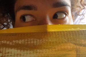 a womens eyes with face covered by gold cloth