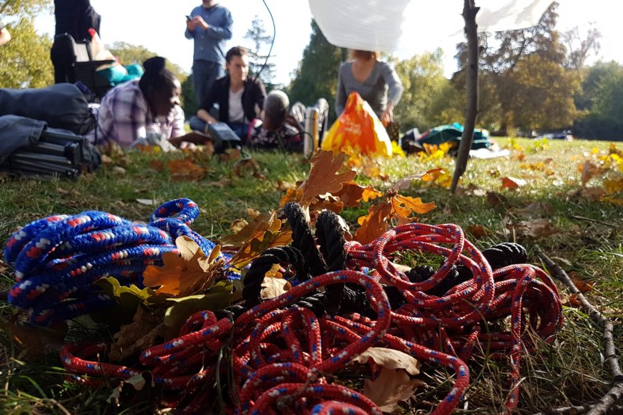 people in the distance in a park. a pile of rope on the grass.