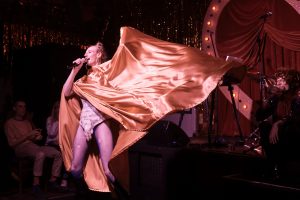 Person dressed up in costume with a large gold cape being waved around.