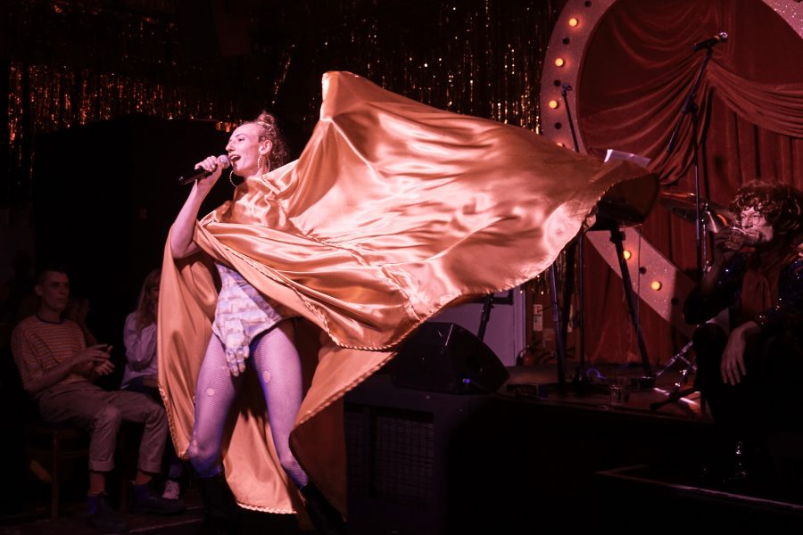 Person dressed up in costume with a large gold cape being waved around.