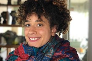 Portrait of Yolande, a woman with brown curly hair wearing a colourful scarf