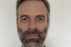 A portrait of Mike, a white man with grey hair and beard