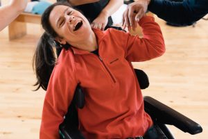 A woman with long dark hair in a wheelchair, smiling