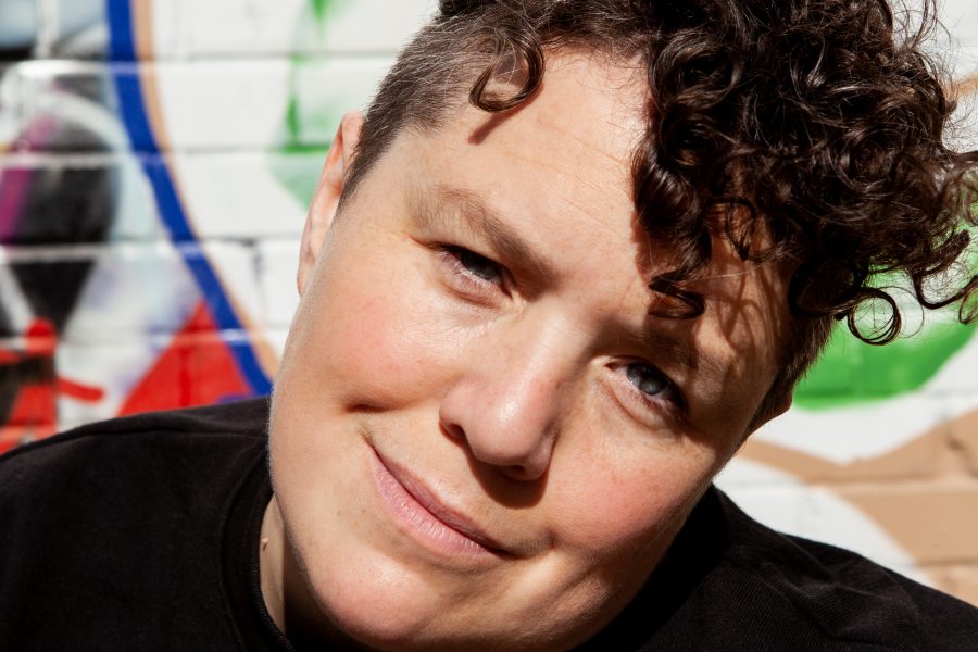 A white woman with short curly brown hair smiling at the camera